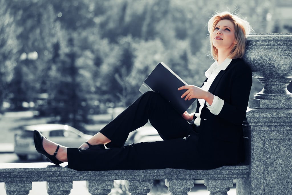 Young business woman with a folder sitting on the banister